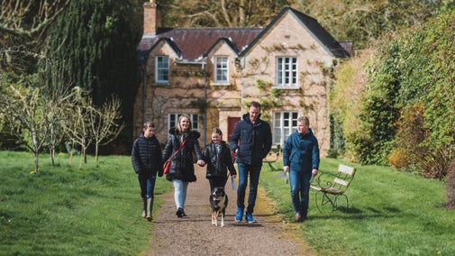 A family walking by Florence Court Rose Cottage, County Fermanagh, Northern Ireland. A charming gardener's cottage with an apple orchard view at Florence Court.